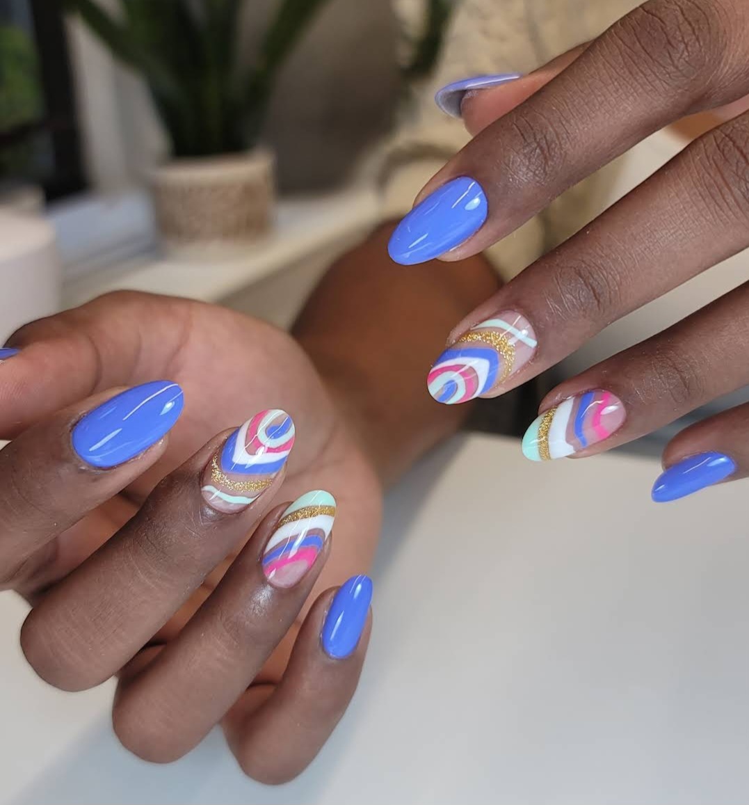 Abstract blue and pink wave nail art with gold accents